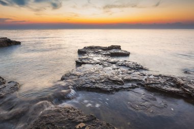 Adriyatik Denizi kıyısında Istria Hırvatistan 'da kayaları olan bir plajda renkli bir gün batımı