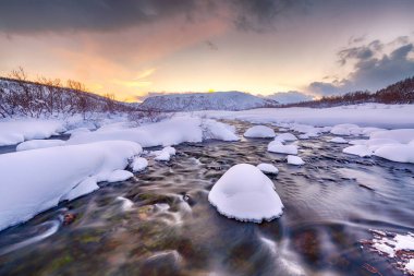 Küçük bir su akışı buzlu arctic, karlı kış manzara, arka plan ile ön plan ile. Gökyüzü olduğunu temizleyin, birden çok ve canlı renkler günbatımı sırasında görülebilir.