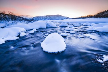Küçük bir su akışı buzlu arctic, karlı kış manzara, arka plan ile ön plan ile. Gökyüzü olduğunu temizleyin, birden çok ve canlı renkler günbatımı sırasında görülebilir.