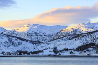 Karlı dağ zirveleri kış günbatımı sırasında bir İskandinav fiyort, üzerinde yakından görmek