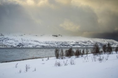 Karlı dağ zirveleri bir İskandinav fiyort bir kar fırtınası sırasında üzerinde yakından görmek