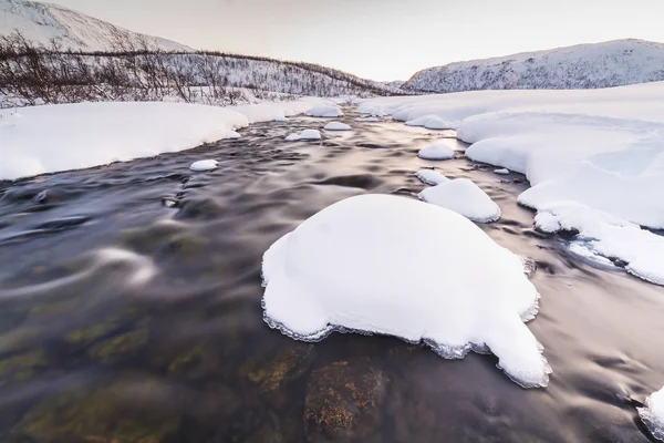 バック グラウンドで北極 雪に覆われた冬の風景と前景の岩と小さな水の流れ 空はクリア 複数と鮮やかな色は 日没時に表示されます — ストック写真