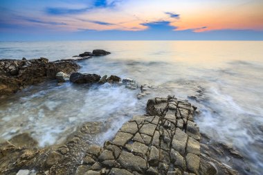 Adriyatik Denizi kıyısında Istria Hırvatistan 'da kayaları olan bir plajda renkli bir gün batımı