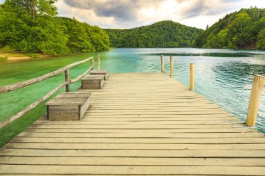 Dağlar ile yeşil ağaçlar ve mavi gökyüzü ve su ile yaz güneşli manzara. Plitvice Gölleri, Hırvatistan
