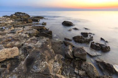 Adriyatik Denizi kıyısında Istria Hırvatistan 'da kayaları olan bir plajda renkli bir gün batımı