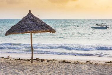 Açık mavi su ile gün batımında şemsiye plaj donanımları tropikal bir Plajı'nda doğal malzemelerden yapılmış ve güneş ışığı etkisi flare
