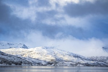 Karlı dağ zirveleri bir İskandinav fiyort bir kar fırtınası sırasında üzerinde yakından görmek