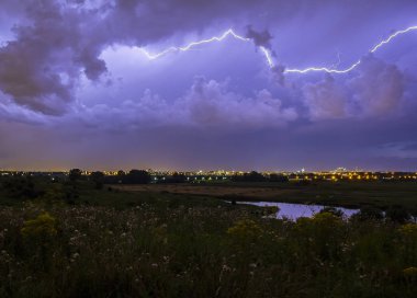Intracloud Yıldırım Yıldırım IC gece bir şehir üzerinde iş başında. Dramatik doğa fırtına, hills çiçekler ön, arka planda şehir ile