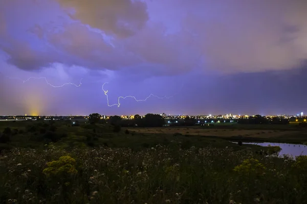 Intracloud lightning thunderbolt IC strikes at night above a cit