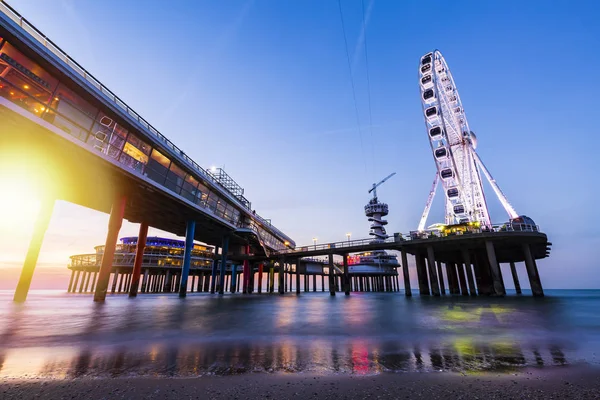 Barevné modrá hodina západ slunce na pobřeží, pláž, molo a ferris w — Stock fotografie