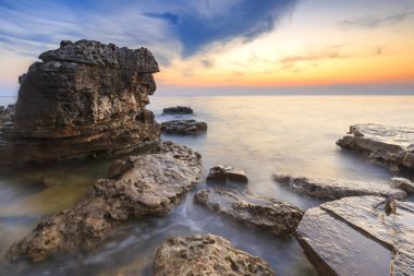 Adriat üzerinde taşlarla bir plajda renkli Günbatımı keyfi