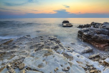 Adriat üzerinde taşlarla bir plajda renkli Günbatımı keyfi