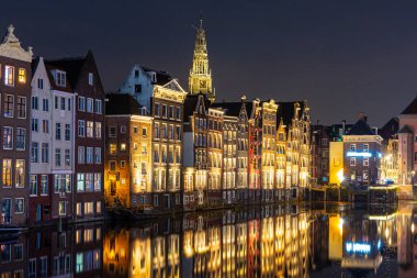 Amsterdam Damrak geleneksel Hollanda mimarisi geceleri. Ön planda tur tekneleri.