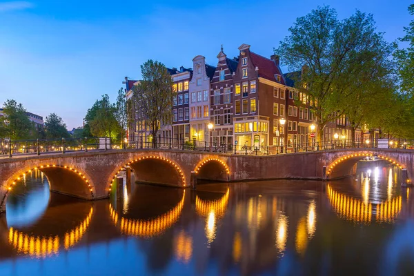Alacakaranlıkta Amsterdam sokakları ve kanalları. Köprüler aydınlandı, yaz mevsimi. Turistler için popüler seyahat yeri.