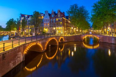 Alacakaranlıkta Amsterdam sokakları ve kanalları. Köprüler aydınlandı, yaz mevsimi. Turistler için popüler seyahat yeri.