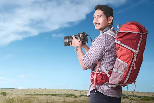 Smiling Asian tourist with backpack and camera outdoor