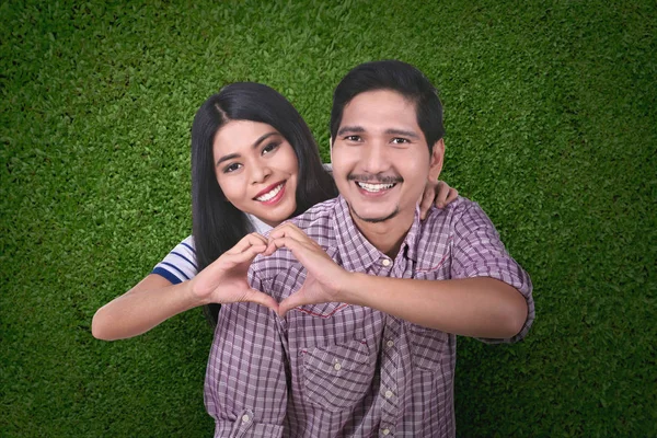幸福的亚洲情侣在爱做心脏形状用手在绿色背景下 — 图库照片