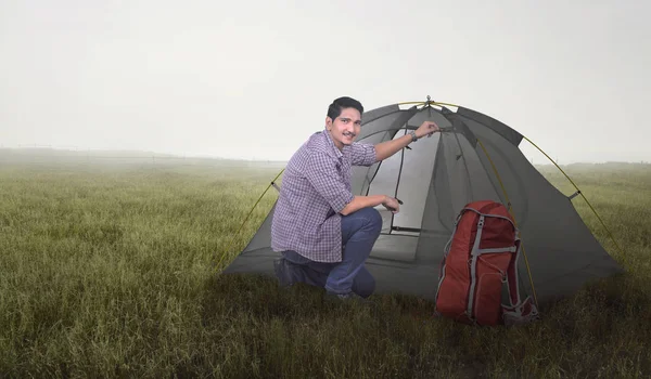 愉快的亚洲游人与背包准备帐篷在草甸领域 — 图库照片