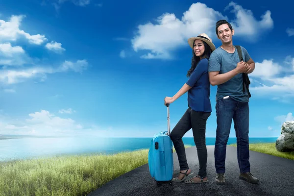 Happy asian traveler couple with bag standing on the road with blue sky background