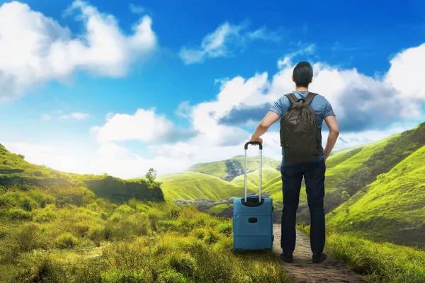 Young asian tourist man with backpack enjoying view at nature with blue sky background