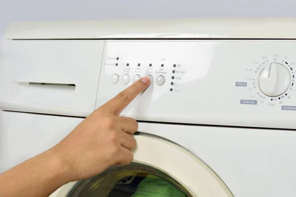 手的特写按在白色背景被隔绝的洗衣机的按钮 — 图库照片