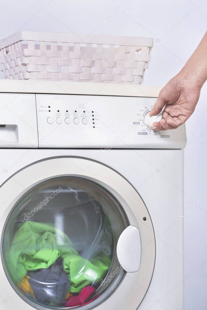 Male hand setting the program on washing machine. Home appliance
