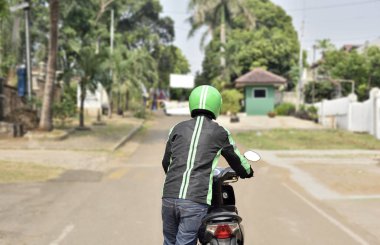 Arkadan Görünüş onun motosiklet kenarında iterek motosiklet taksi sürücüsü