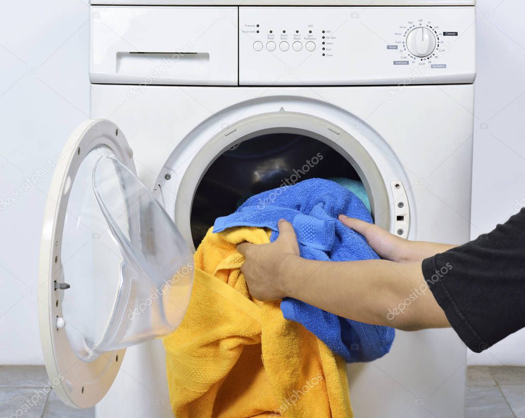 Man loading the dirty towels into washing machine for washed in home