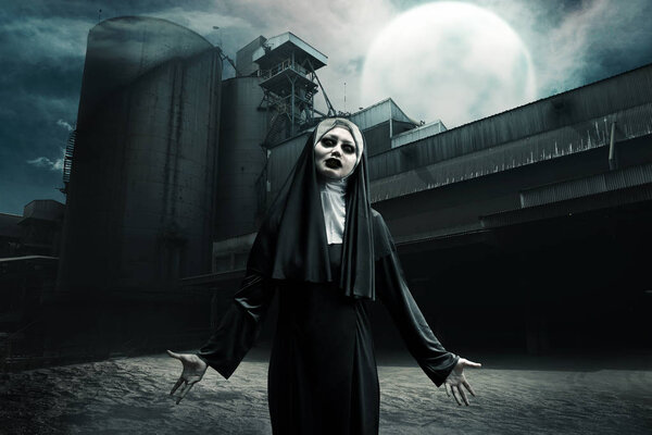 Scary asian devil nun standing on abandoned old factory at midnight
