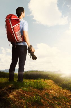 Genç Asyalı adam sırt çantası ve gündoğumu manzarayı açık, kamera