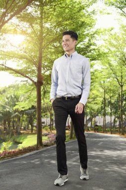 Parkta üzerinde dolaşan mutlu Asya iş adamı 