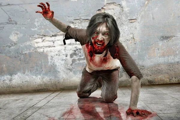 Angry zombie man with bloody mouth crawling over grunge wall background