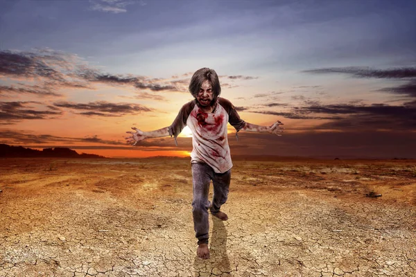 可怕的僵尸男子与血腥的衣服站在干燥的土地上 — 图库照片
