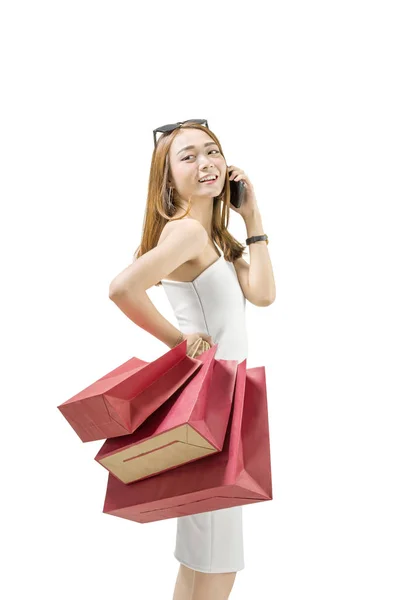 微笑的亚洲女孩与购物袋谈论手机查出的白色背景 — 图库照片