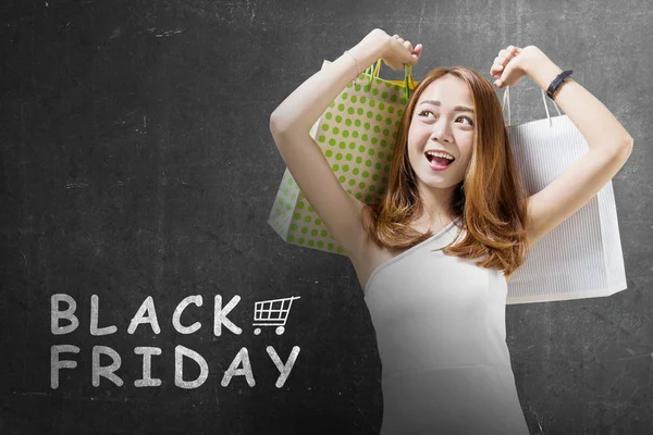 Happy asian woman with colored shopping bags. Black friday concept