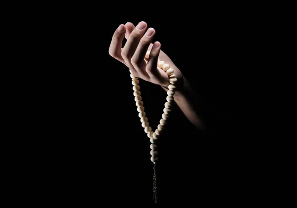 Man hands praying with prayer beads over dark background. Muslim Pray