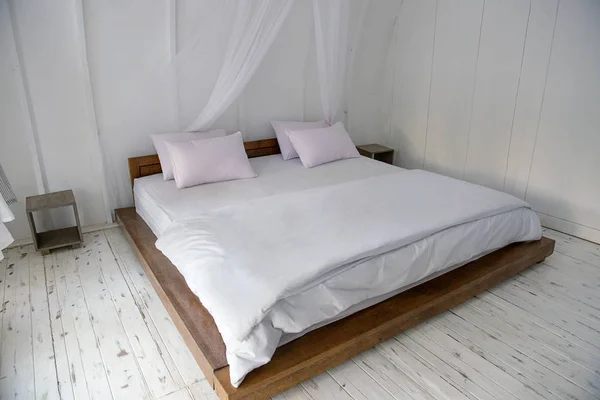 Interior of wooden cottage with large bed and white wall. Wooden cottage on Sumbawa, Indonesia