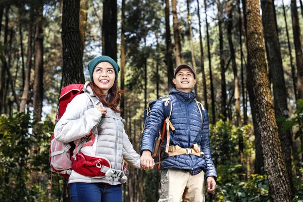 愉快的亚洲徒步旅行者夫妇与背包走 而牵手在森林 — 图库照片