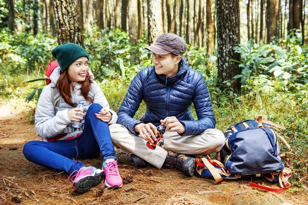 微笑的亚洲情侣徒步者一边休息 一边在森林里喝水 — 图库照片