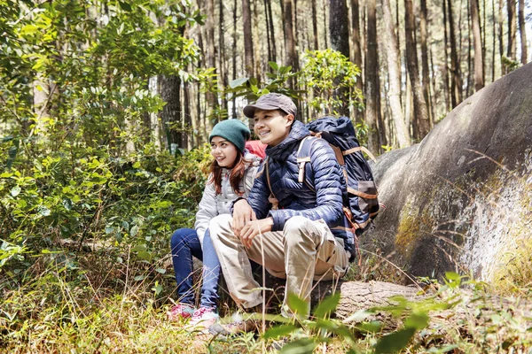 愉快的亚洲夫妇徒步旅行者坐在树干上 而休息在森林上 — 图库照片