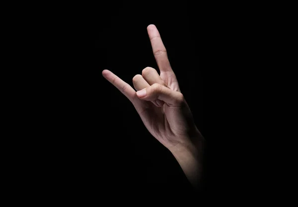 Male hands with rock or metal music gesture over dark background
