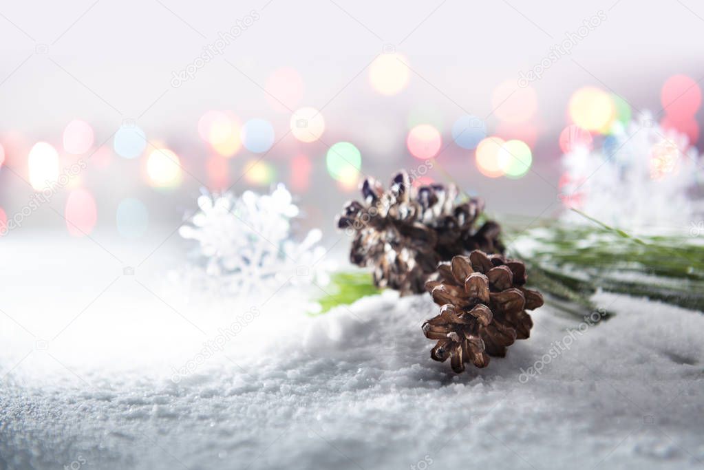 Pine cones on snow with blurred lights background. Christmas decoration