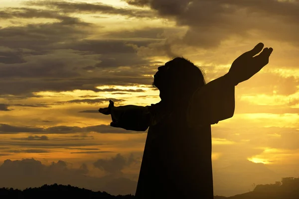 イエス キリストのシルエット夕日を背景に調達の腕の側に立って — ストック写真