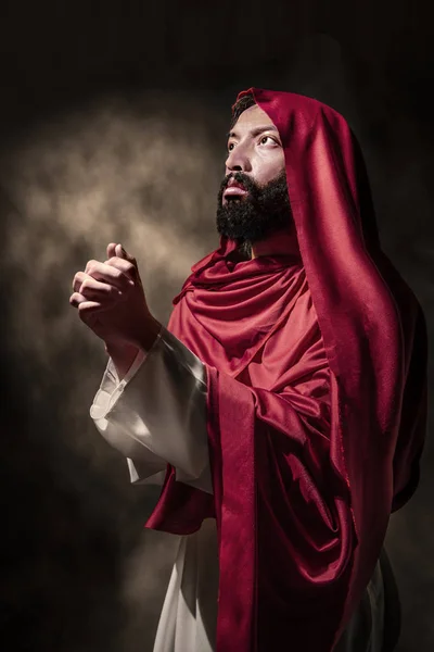 Jesus christ praying to god with hand gesture over black background