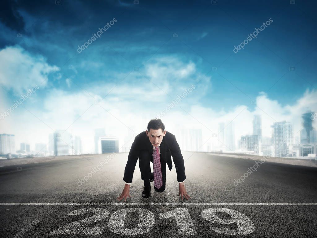 Attractive asian businessman ready to run on the street with 2019 number on starting line. Happy New Year 2019