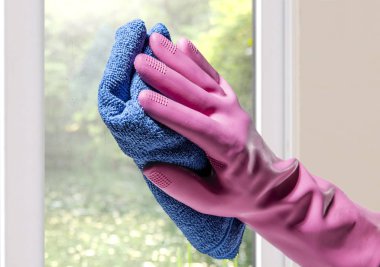 Elinde lastik eldiven ve mikro fiber kumaştan pencere cam evde temizlik