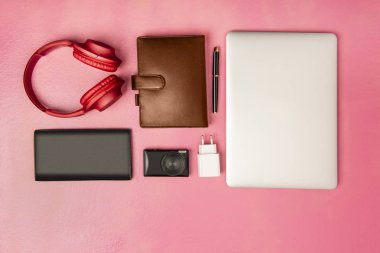 dizüstü bilgisayar, kalem, defter, kamera, m-cüzdan ve kulaklık iş için en iyi görünümü pembe bir arka plan üzerinde. Yukarıdan görüntülemek