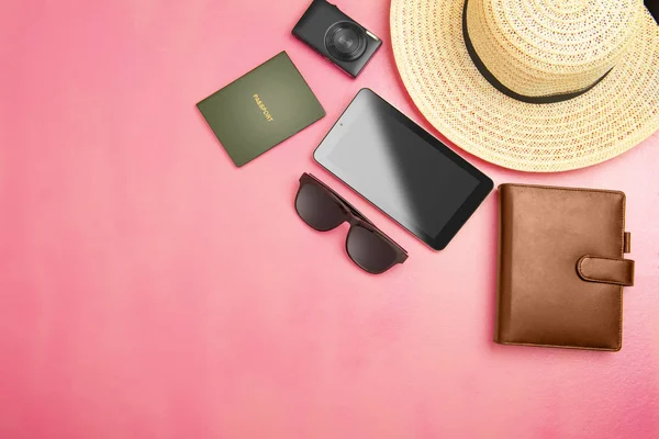 top view of hat, wallet, camera, tablet, sunglasses and passport for traveling on pink background. View from above