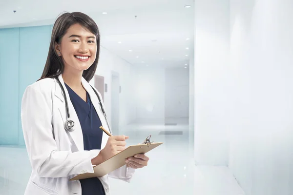 Sorrindo Asiático Médico Mulher Vestindo Jaleco Escrevendo Notas Área Transferência — Fotografia de Stock