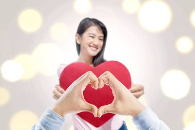 Adam elleriyle kalp şekli ve Asyalı kadın kalp kırmızı kağıt basılı tutarak ayakta. Sevgililer günü